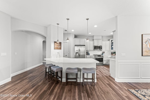1649 Tullagee Ave, Melbourne, FL 32940 - kitchen featuring stainless steel appliances, a kitchen breakfast bar, a peninsula, arched walkways, and dark wood-style flooring