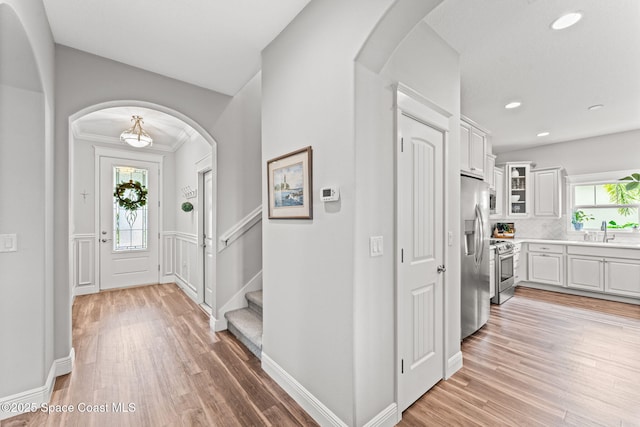 1649 Tullagee Ave, Melbourne, FL 32940 - entryway featuring light wood finished floors, recessed lighting, arched walkways, stairs, and a wainscoted wall