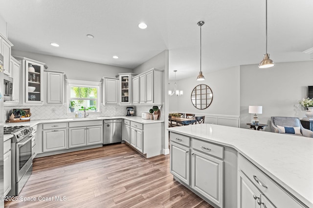 1649 Tullagee Ave, Melbourne, FL 32940 - kitchen featuring stainless steel appliances, tasteful backsplash, light wood-style flooring, light countertops, and hanging light fixtures