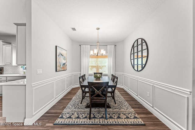 1649 Tullagee Ave, Melbourne, FL 32940 - dining area featuring a chandelier, dark wood-type flooring, a decorative wall, and wainscoting