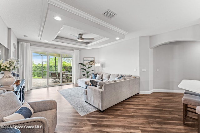 1649 Tullagee Ave, Melbourne, FL 32940 - living area featuring ceiling fan, arched walkways, dark wood-type flooring, a tray ceiling, and ornamental molding