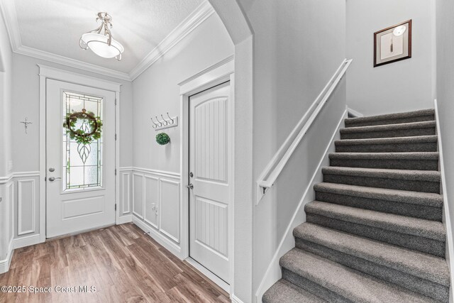 1649 Tullagee Ave, Melbourne, FL 32940 - entryway with crown molding, arched walkways, stairway, wood finished floors, and a decorative wall