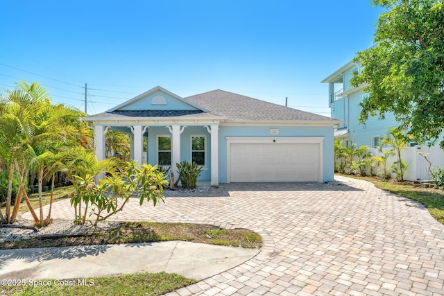 1121 S Orlando Ave, Cocoa Beach, FL 32931 - view of front facade featuring decorative driveway, an attached garage, covered porch, roof with shingles, and stucco siding