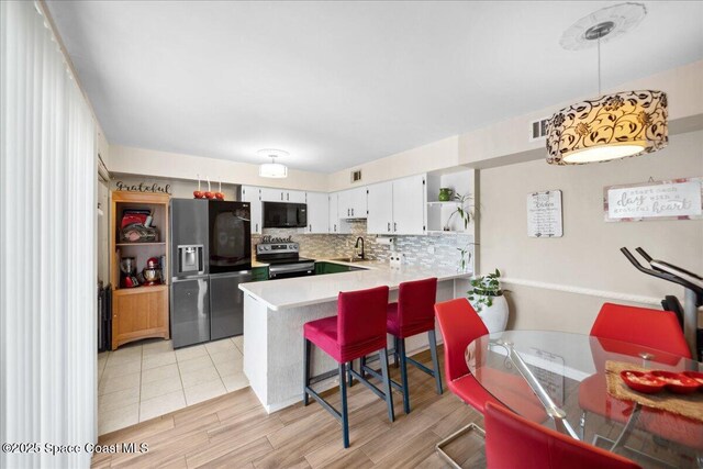 1020 Abada Ct NE Unit 108, Palm Bay, FL 32905 - kitchen featuring appliances with stainless steel finishes, open shelves, a peninsula, light countertops, and light wood-style flooring