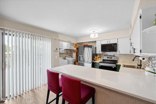 1020 Abada Ct NE Unit 108, Palm Bay, FL 32905 - kitchen featuring stainless steel appliances, separate washer and dryer, a peninsula, light countertops, and decorative backsplash