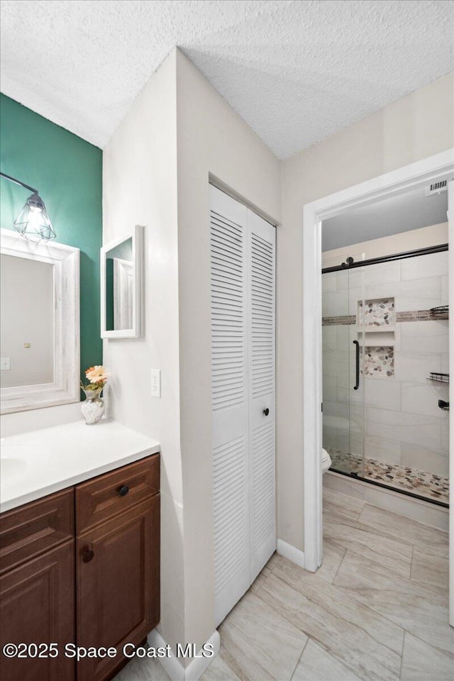 1020 Abada Ct NE Unit 108, Palm Bay, FL 32905 - full bathroom featuring a closet, vanity, a stall shower, and a textured ceiling