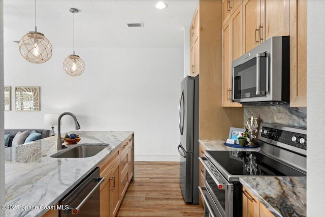 833 Paddleboard Ct, Melbourne, FL 32935 - kitchen featuring stainless steel appliances, light wood-type flooring, light stone counters, hanging light fixtures, and light brown cabinets