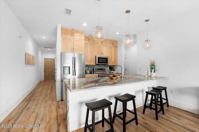 833 Paddleboard Ct, Melbourne, FL 32935 - kitchen featuring stainless steel appliances, light brown cabinets, a peninsula, a kitchen breakfast bar, and recessed lighting
