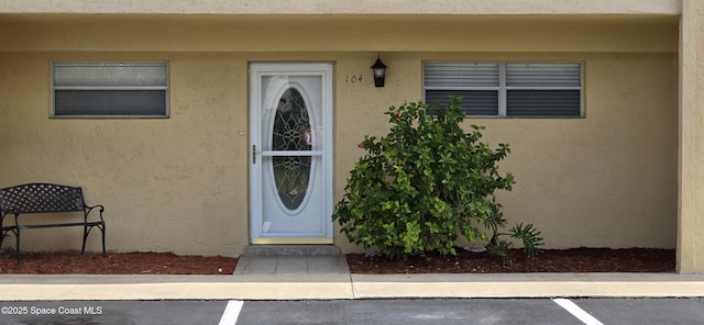 2135 N Courtenay Pkwy Unit 104, Merritt Island, FL 32953 - view of exterior entry featuring stucco siding and uncovered parking