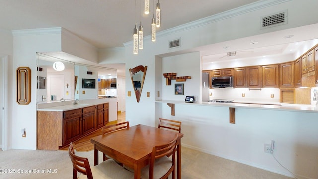 905 N Harbor City Blvd Unit 403, Melbourne, FL 32935 - kitchen featuring stainless steel microwave, light carpet, ornamental molding, light countertops, and brown cabinetry