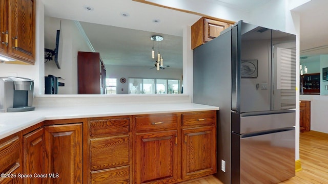 905 N Harbor City Blvd Unit 403, Melbourne, FL 32935 - kitchen with freestanding refrigerator, brown cabinetry, light wood-style flooring, light countertops, and a ceiling fan
