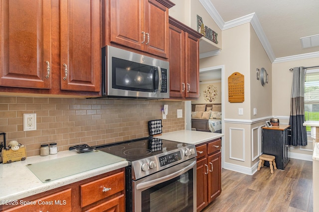 231 Nardo Ave SW, Palm Bay, FL 32908 - kitchen with stainless steel appliances, ornamental molding, light countertops, wood finished floors, and wainscoting