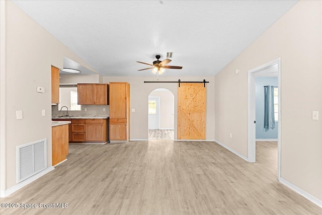 5510 Holden Rd, Cocoa, FL 32927 - unfurnished living room featuring ceiling fan, light wood-style floors, arched walkways, a barn door, and a textured ceiling