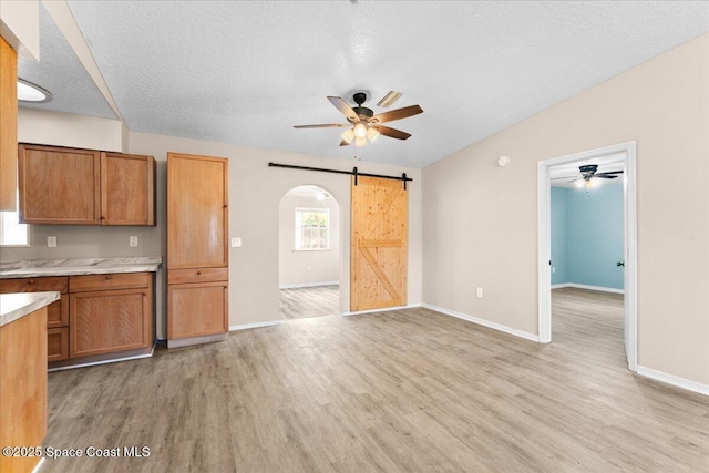 5510 Holden Rd, Cocoa, FL 32927 - kitchen with a barn door, a ceiling fan, light wood finished floors, brown cabinetry, and light countertops