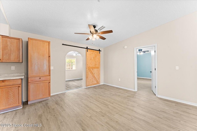 5510 Holden Rd, Cocoa, FL 32927 - unfurnished living room featuring a barn door, ceiling fan, light wood finished floors, and arched walkways