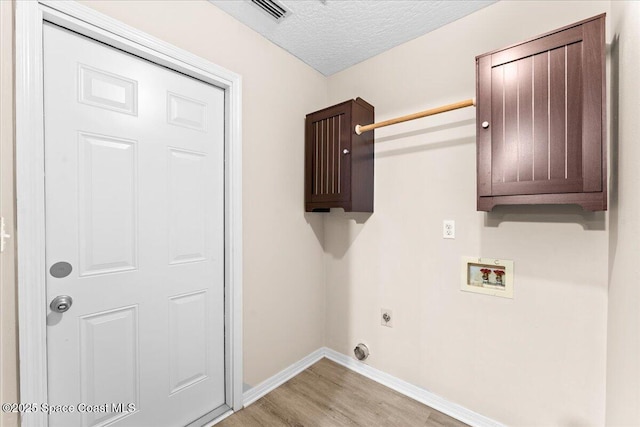 5510 Holden Rd, Cocoa, FL 32927 - washroom with light wood-style flooring, washer hookup, hookup for an electric dryer, cabinet space, and a textured ceiling