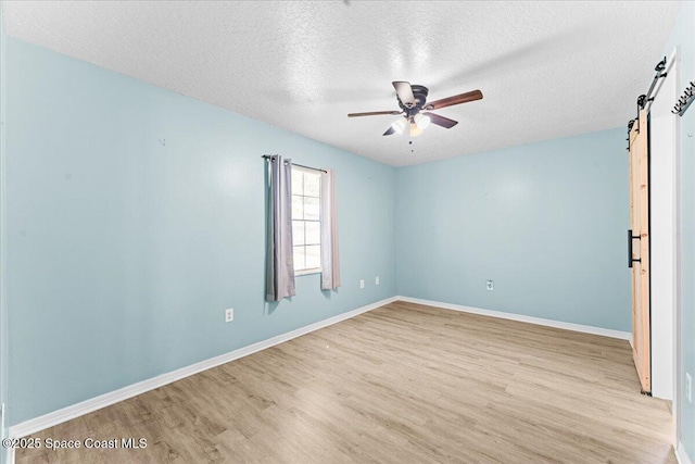 5510 Holden Rd, Cocoa, FL 32927 - empty room with a barn door, light wood-type flooring, a textured ceiling, and a ceiling fan