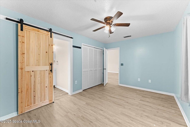 5510 Holden Rd, Cocoa, FL 32927 - unfurnished bedroom with a barn door, wood finished floors, a textured ceiling, and a ceiling fan