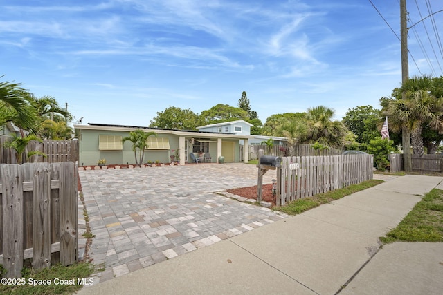 1030 S Orlando Ave, Cocoa Beach, FL 32931 - view of front facade with decorative driveway, a fenced front yard, a garage, and solar panels