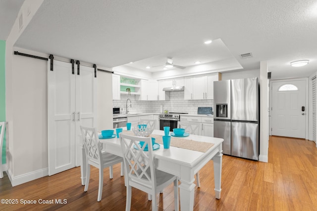 1710 Atlantic St Unit 5E, Melbourne Beach, FL 32951 - kitchen featuring stainless steel appliances, a raised ceiling, ceiling fan, backsplash, and white cabinets