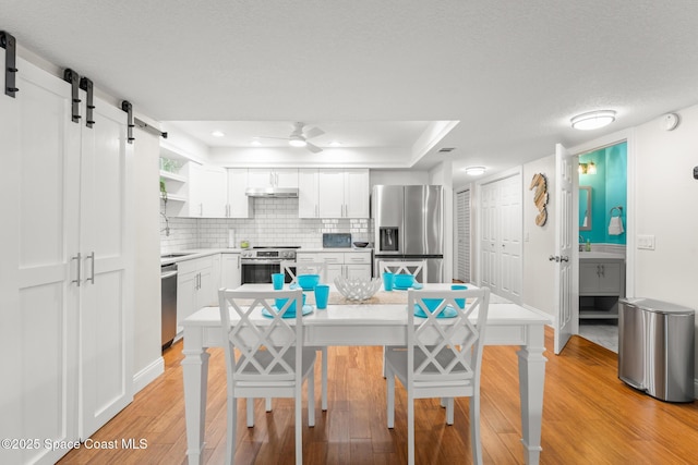 1710 Atlantic St Unit 5E, Melbourne Beach, FL 32951 - kitchen with stainless steel appliances, light wood finished floors, a ceiling fan, under cabinet range hood, and white cabinets