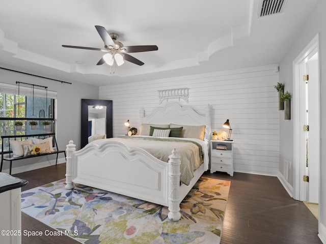 3662 Brantley Cir, Rockledge, FL 32955 - bedroom featuring a tray ceiling, dark wood-type flooring, wooden walls, and ceiling fan