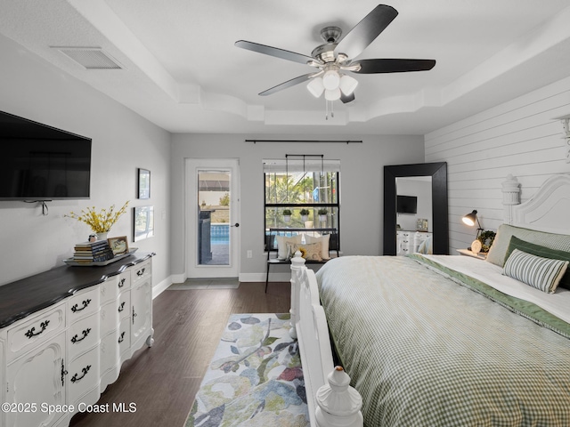 3662 Brantley Cir, Rockledge, FL 32955 - bedroom featuring a tray ceiling, multiple windows, dark wood-style floors, ceiling fan, and wooden walls
