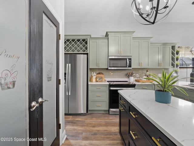 3662 Brantley Cir, Rockledge, FL 32955 - kitchen featuring appliances with stainless steel finishes, decorative backsplash, a chandelier, light stone countertops, and dark wood finished floors