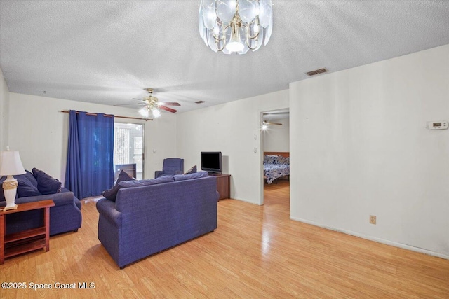 1289 Cheney Hwy Unit B, Titusville, FL 32780 - living room featuring light wood-style flooring, a ceiling fan, a chandelier, and a textured ceiling