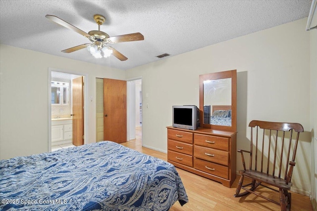 1289 Cheney Hwy Unit B, Titusville, FL 32780 - bedroom featuring light wood-type flooring, a textured ceiling, connected bathroom, and a ceiling fan