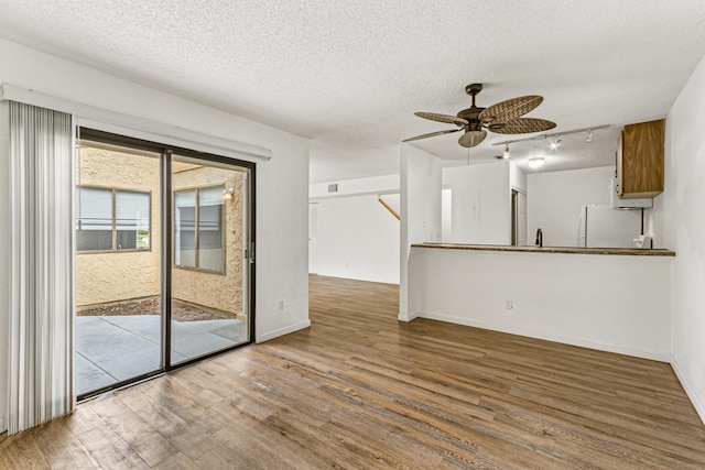 1441 Sheafe Ave NE Unit 104, Palm Bay, FL 32905 - unfurnished living room featuring wood finished floors, a ceiling fan, a textured ceiling, and rail lighting