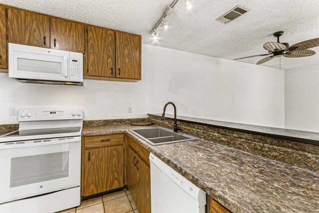 1441 Sheafe Ave NE Unit 104, Palm Bay, FL 32905 - kitchen with white appliances, a textured ceiling, dark countertops, brown cabinetry, and light tile patterned floors
