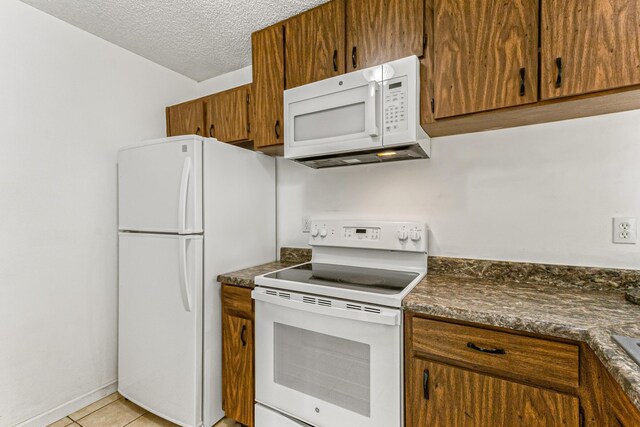 1441 Sheafe Ave NE Unit 104, Palm Bay, FL 32905 - kitchen with white appliances, dark countertops, brown cabinets, a textured ceiling, and light tile patterned floors