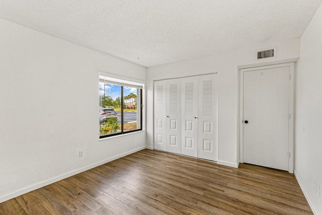 1441 Sheafe Ave NE Unit 104, Palm Bay, FL 32905 - unfurnished bedroom with wood finished floors, a closet, and a textured ceiling