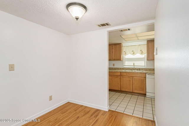 2358 Golf Lake Cir Unit 212, Melbourne, FL 32935 - kitchen featuring dishwasher, light wood-style floors, light countertops, brown cabinets, and a textured ceiling