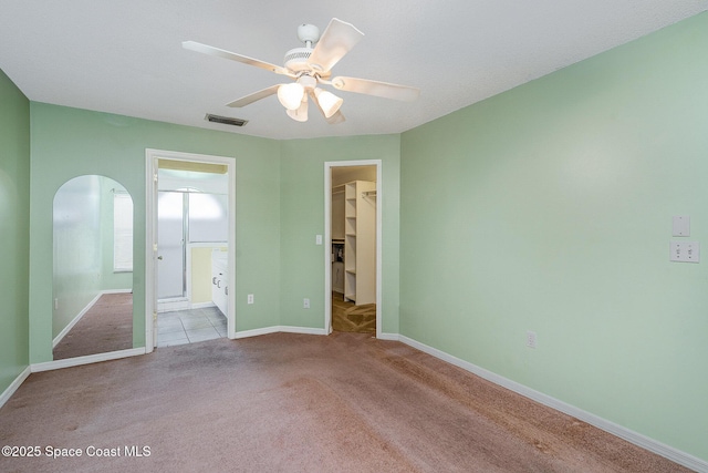 146 Oakcrest Ave NE, Palm Bay, FL 32907 - unfurnished bedroom featuring carpet, a spacious closet, arched walkways, a closet, and ensuite bath