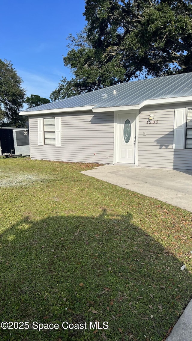 1385 Salerno Ave SE, Palm Bay, FL 32909 - view of front of property with a front lawn, a metal roof, and a patio