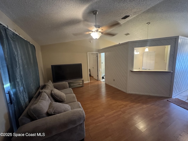 1385 Salerno Ave SE, Palm Bay, FL 32909 - living area with wood finished floors, vaulted ceiling, a ceiling fan, and a textured ceiling