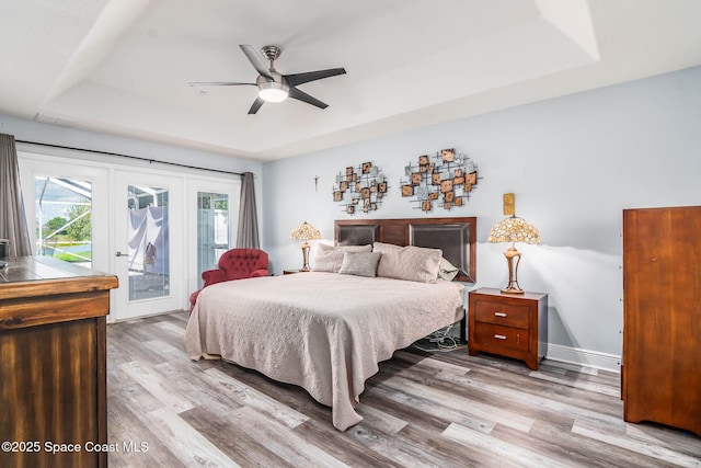 4448 Heaton Park Trl, Rockledge, FL 32955 - bedroom featuring a tray ceiling, access to exterior, light wood finished floors, and ceiling fan
