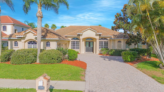 4180 Stoney Point Rd, Melbourne, FL 32940 - mediterranean / spanish-style home featuring stucco siding, a front lawn, decorative driveway, and a tile roof
