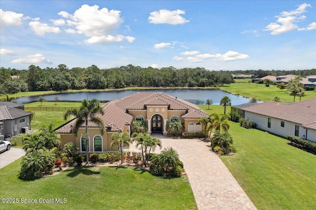 4464 Preservation Cir, Melbourne, FL 32934 - mediterranean / spanish-style home featuring a water view, decorative driveway, a tiled roof, stucco siding, and a front yard
