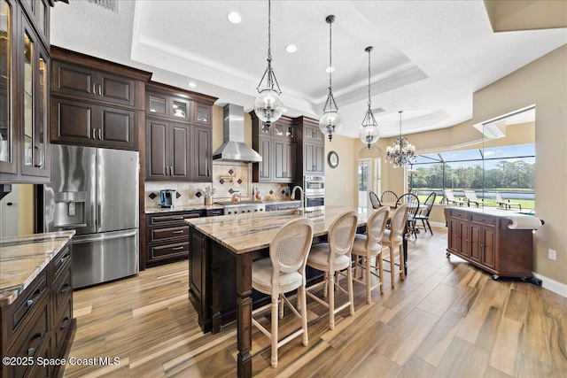 4464 Preservation Cir, Melbourne, FL 32934 - kitchen featuring wall chimney exhaust hood, appliances with stainless steel finishes, a raised ceiling, a chandelier, and recessed lighting