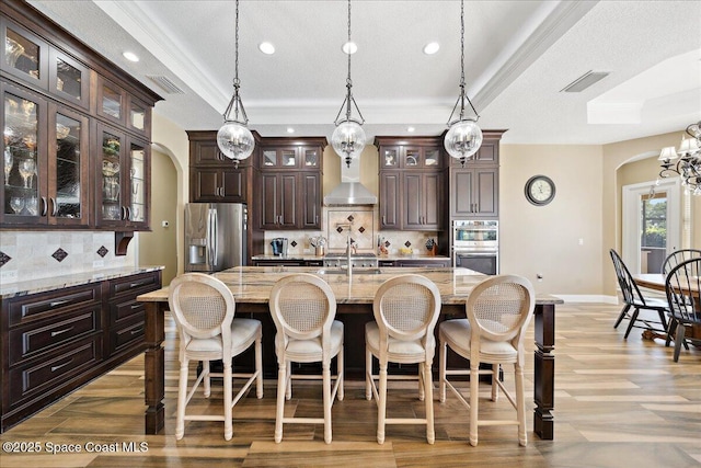 4464 Preservation Cir, Melbourne, FL 32934 - kitchen featuring appliances with stainless steel finishes, arched walkways, recessed lighting, tasteful backsplash, and dark brown cabinets