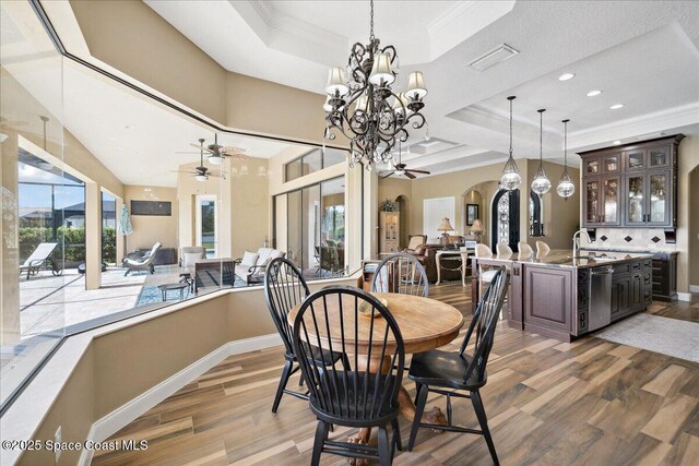 4464 Preservation Cir, Melbourne, FL 32934 - dining room featuring a raised ceiling, ceiling fan, arched walkways, light wood-style floors, and crown molding