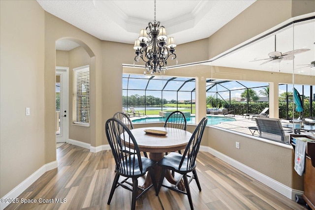 4464 Preservation Cir, Melbourne, FL 32934 - dining space with a tray ceiling, crown molding, wood finished floors, arched walkways, and ceiling fan
