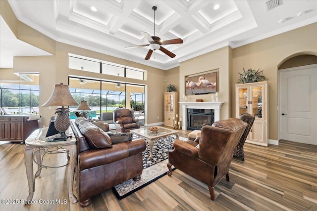 4464 Preservation Cir, Melbourne, FL 32934 - living area with wood finished floors, a glass covered fireplace, ceiling fan, ornamental molding, and beamed ceiling