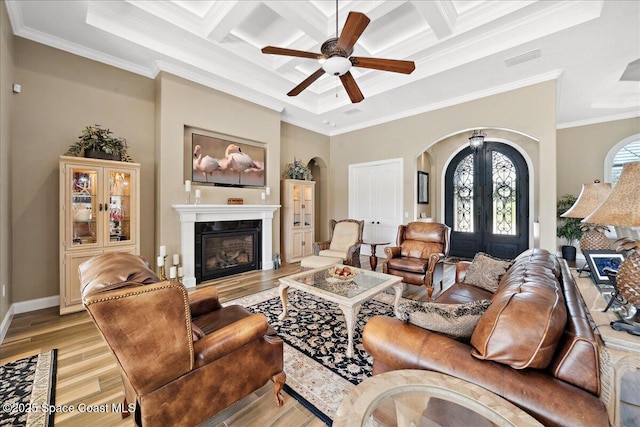 4464 Preservation Cir, Melbourne, FL 32934 - living room featuring arched walkways, crown molding, a glass covered fireplace, a ceiling fan, and light wood finished floors