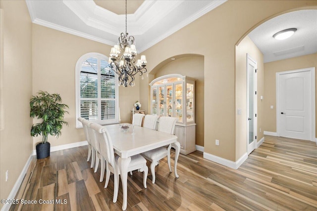 4464 Preservation Cir, Melbourne, FL 32934 - dining area with arched walkways, a chandelier, wood finished floors, crown molding, and a raised ceiling