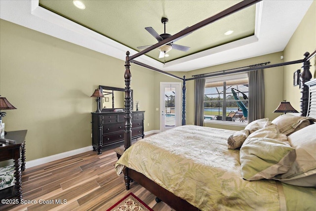 4464 Preservation Cir, Melbourne, FL 32934 - bedroom with a tray ceiling, wood finished floors, a ceiling fan, recessed lighting, and access to exterior