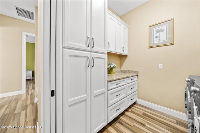 4464 Preservation Cir, Melbourne, FL 32934 - washroom with separate washer and dryer, cabinet space, and light wood finished floors